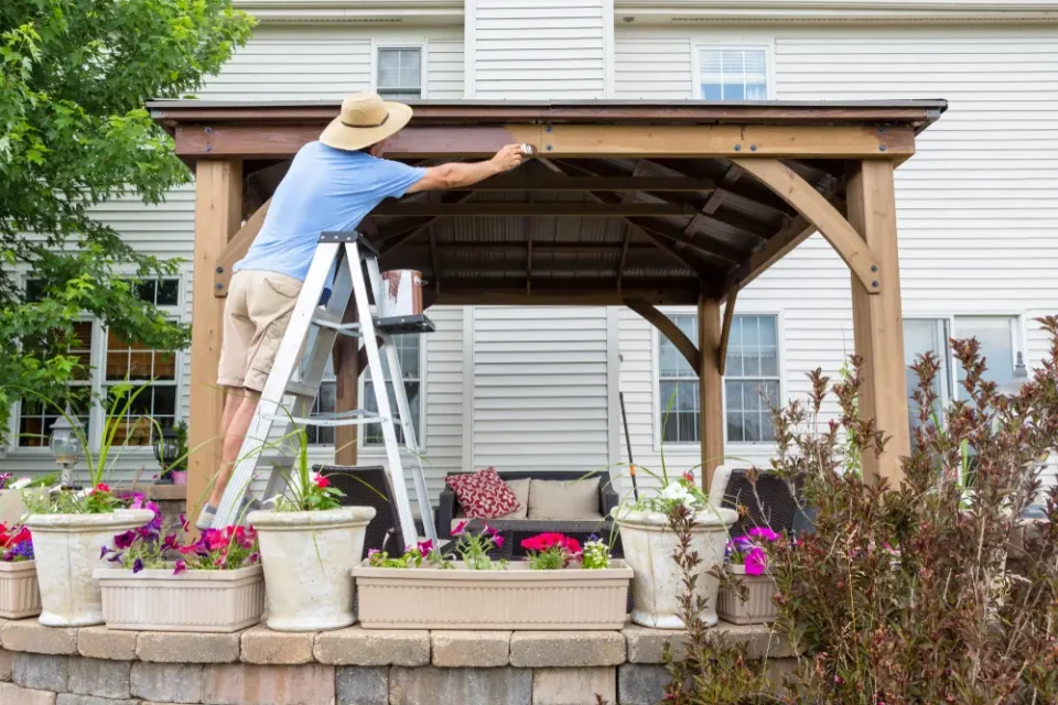 a man on a ladder painting a roof