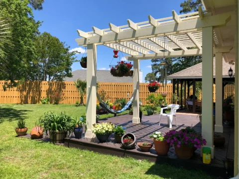 a white pergola with a hammock and flowers