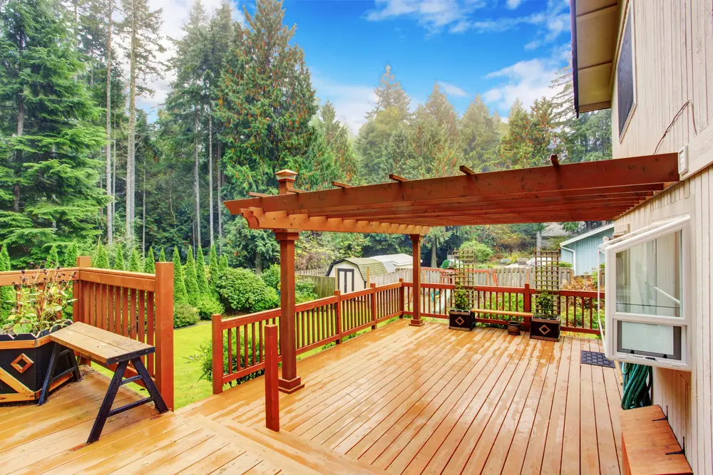 a deck with a pergola and trees in the background