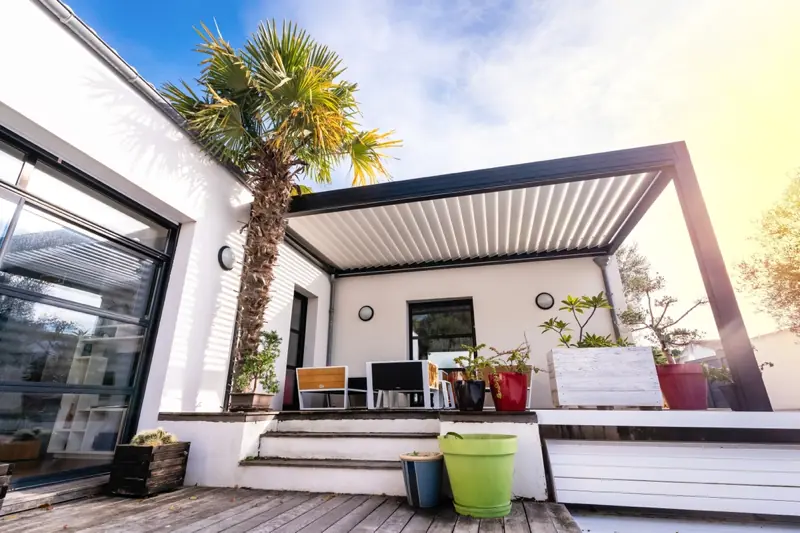 a white house with a palm tree and chairs