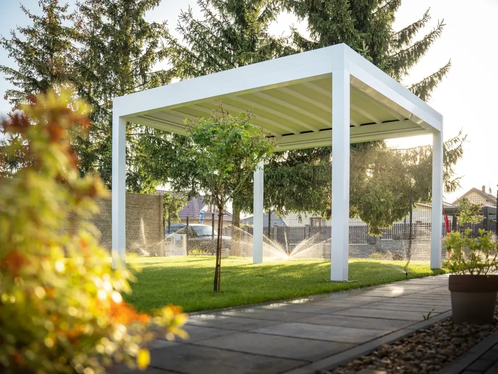 a white structure with sprinklers on the grass